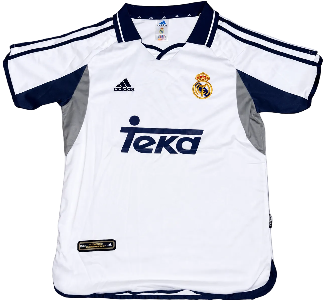 White soccer jersey with navy accents featuring Adidas and Real Madrid logos on a white background