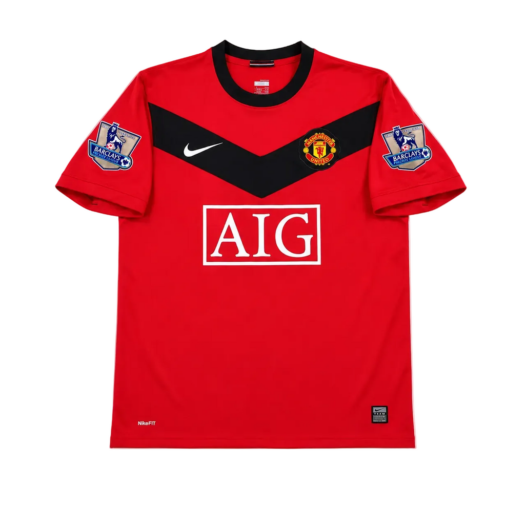 A red and black Manchester United soccer jersey with the AIG sponsor logo on the front, a Nike swoosh, Manchester United crest, and Premier League patches on the sleeves, shown flat on a white background.