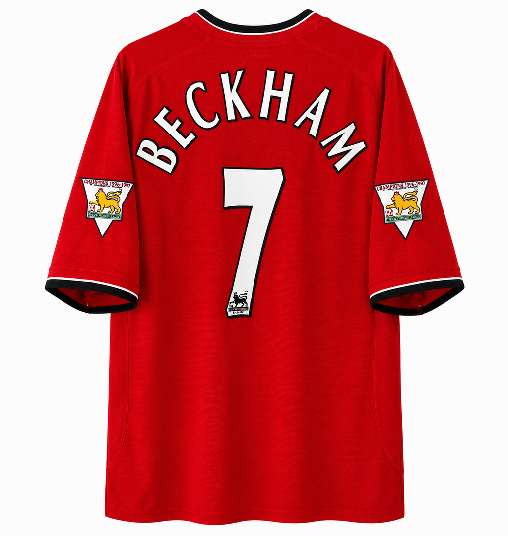 A red long-sleeve football jersey shown from the back, featuring 'BECKHAM' and the number '7' in white with black outlines. The sleeves have white triangular patches with the Manchester United crest and text.